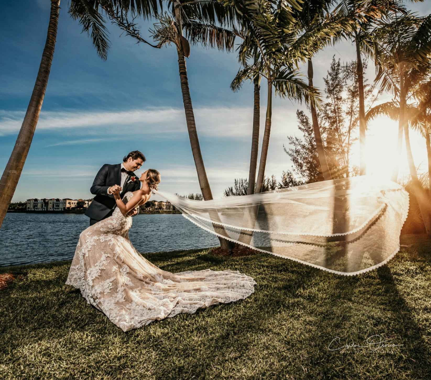 Bride and groom dip pose at sunset with veil catching golden light — Carlos Osorio Miami wedding photography